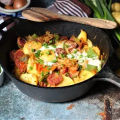 Herzhafte Bauernpfanne mit Ei, Kartoffeln, Wurst und Gemüse, garniert mit Schnittlauch. Ein deftiges Gericht für jeden Tag.
