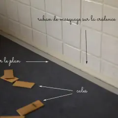 Préparation pour la pose d'un nouveau plan de travail : ruban de masquage sur la crédence et cales en bois sur le plan actuel.
