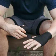 A boxer wraps his hands, ensuring the wraps are snug but not too tight. This is key to protecting his knuckles and wrists during a fight.