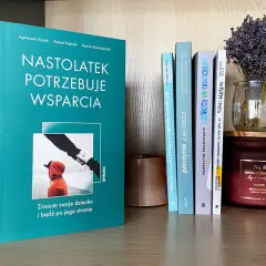 Książka "Nastolatek potrzebuje wsparcia" na półce z innymi książkami i świecą.