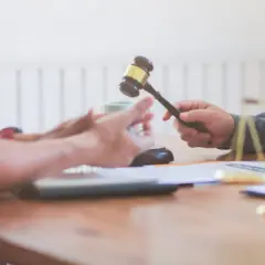 Sąd orzeka, kiedy uchwała wspólnoty mieszkaniowej jest nieważna. Młotek sędziowski w dłoniach.