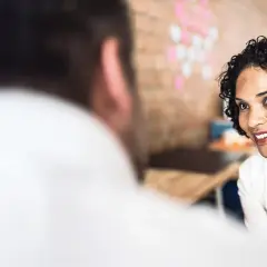 Eine lächelnde Psychotherapeutin im Gespräch mit einem Patienten. Sie strahlt Empathie aus, was für die IU Psychologie wichtig ist.