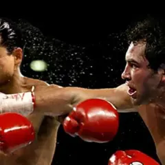 Mario Lopez in a boxing match, caught mid-punch as sweat flies.