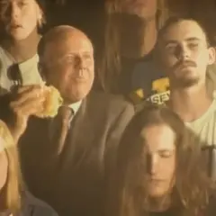 Tłum ludzi, wśród nich starszy mężczyzna jedzący burgera. Atmosfera jest mroczna, ale czuć w niej energię, jakby to był koncert, który pachnie nirwaną.