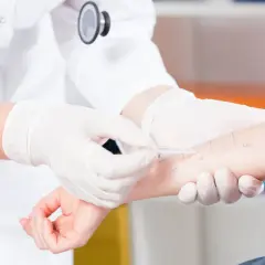 Lekarz w białej rękawiczce wykonuje test skórny na przedramieniu pacjenta.
