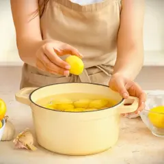 Hände legen Kartoffeln in einen Topf mit Wasser. Die Kochzeit für Kartoffeln beginnt jetzt.