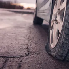 Pneu à plat sur la route mouillée, nécessitant une réparation de crevaison.