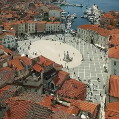 Słowenia morze: malowniczy plac w Piran, z widokiem na dachy i port.