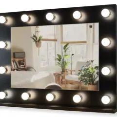 Eleganckie, **czarne lustro stojące** z oświetleniem LED, idealne do garderoby. Odbija przytulne wnętrze z roślinami.