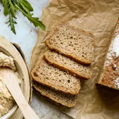 Chleb żytni, pokrojony w kromki, obok miski z pastą. Czy żyto ma gluten? Tak, żytnie pieczywo zawiera gluten.