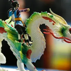Ein Junge reitet auf einem weißen Drachen mit grünen und roten Akzenten. Ein detailreiches Schleich Spielzeug, das Fantasie und Abenteuer weckt.