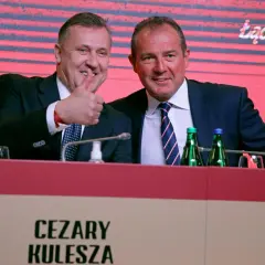 Cezary Kulesza, z synem, uśmiechnięci, z kciukiem w górze, podczas konferencji.