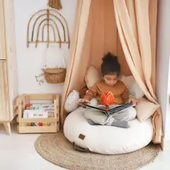 Niña en un acogedor montessori rincón de lectura niños, absorta en un libro pop-up.