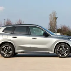 Srebrny, niezawodny SUV BMW X1 stoi na parkingu. Elegancki design i sportowe felgi podkreślają jego charakter.