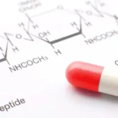 Czerwona kapsułka na tle wzoru chemicznego. Zastanawiasz się, ile się czeka na wyniki badań krwi na narkotyki policja?