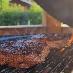 Två saftiga biffar med kryddor grillas över glödande kol. Perfekt för en sommarfest, undrar vad man kan grilla mer?