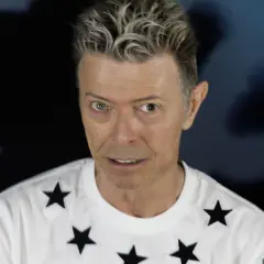 Ikoniczny David Bowie w 2016 roku, w białej koszulce w czarne gwiazdy, z charakterystyczną fryzurą.