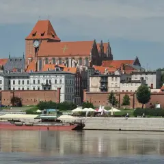 Widok na średniowieczny zespół miejski Torunia z Wisły. Widać katedrę, mury obronne i kamienice.