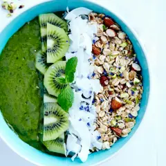 En grön, nyttig smoothie bowl med kiwi, kokosflingor och granola.