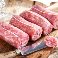 Frische Salsiccia-Würste auf Holzbrett, Messer mit Scheibe. Die korrekte Salsiccia Aussprache ist wichtig für den Genuss.