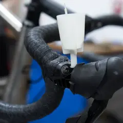 A white funnel attached to a bicycle handlebar, part of an easy way to bleed brakes.