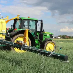Zielony traktor z opryskiwaczem na polu. Warto sprawdzić movento 100 sc dawkowanie dla optymalnych rezultatów.
