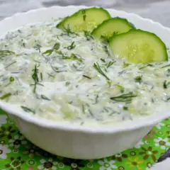 Pyszny, kremowy sos tzatziki z kawałkami ogórka i świeżym koperkiem, ozdobiony plasterkami ogórka. Idealny dodatek do greckich potraw.