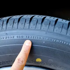 Palec wskazuje na oznaczenie "TREADWEAR 260 TRACTION A TEMPERATURE A" na oponie, informujące o jej właściwościach i dacie produkcji.