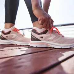 Dłoń zawiązuje sznurówki w różowych butach sportowych. Wyglądają na trochę za duże, ale gotowe do biegu.