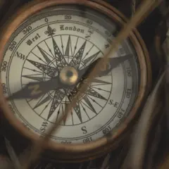 Bussola antica tra l'erba secca, uno strumento che ci fa pensare a chi ha inventato la bussola e alle grandi scoperte.