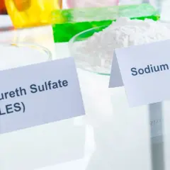 Dwa białe proszki w naczyniach laboratoryjnych: Sodium Laureth Sulfate (SLES) i Sodium Lauryl Sulfate (SLS).