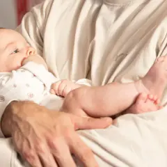 Dziecko trzymane w ramionach, z główką opartą o ramię, może sugerować źle noszenie niemowlaka. Jego nóżki swobodnie zwisają.