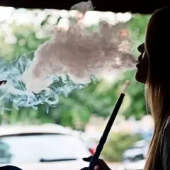 Silhouette einer Frau, die eine Shisha raucht. Dichter Rauch steigt auf und umhüllt ihr Gesicht. Ein **Rauchmelder** wäre hier fehl am Platz.