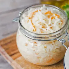 Glas mit Sauerkraut, bereit zum Kohl fermentieren. Frische Kräuter im Hintergrund.