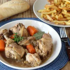 Guiso de pollo con patatas de la abuela, tierno y jugoso, acompañado de patatas fritas crujientes y pan.