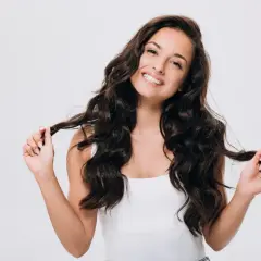 Frau mit vollem, glänzendem Haar, die zeigt, wie man gesunde Haare bekommt.