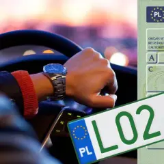 Ręka kierowcy na kierownicy, obok zielone tablice rejestracyjne z numerem L02 84P95 i dowód rejestracyjny.