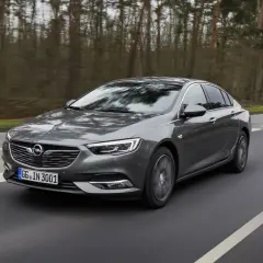 Grå Opel Insignia kör på en väg genom en skog. Kanske ett opel insignia problem med att hitta rätt väg?