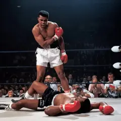 Iconic Muhammad Ali stands over a fallen opponent in the ring, a triumphant roar escaping his lips. A crowd watches, cameras flashing.
