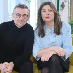 Krzysztof Czeczot z żoną, uśmiechnięci, siedzą na kanapie.