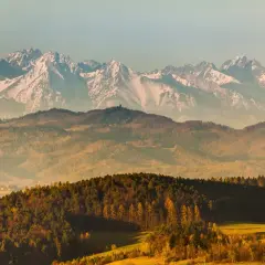 Widok na ośnieżone szczyty Tatr, które górują nad jesiennymi wzgórzami. Piękno polskiej przyrody.