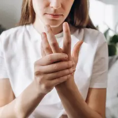 Kobieta masuje dłoń, cierpiąc z powodu bólu rąk w nocy.