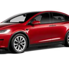 Czerwony Tesla X z czarnym dachem i przyciemnianymi szybami, prezentujący nowoczesny design i elektryczną moc.