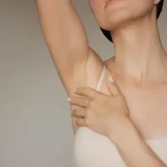 Delikatna skóra pod pachami, gładka dzięki kwasowi glikolowemu. Kobieta dotyka ramienia.