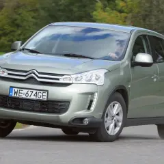 Zielony Citroën C4 Aircross z polskimi tablicami WE 674GE jedzie po drodze wśród zieleni.