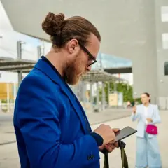 Mężczyzna w niebieskiej marynarce sprawdza telefon, szukając sposobu, jak sprawdzić stan konta bez logowania.