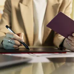 Kobieta z pierścionkami na palcach trzyma dokument i rysik, przygotowując się do przedłużenia profilu zaufanego.