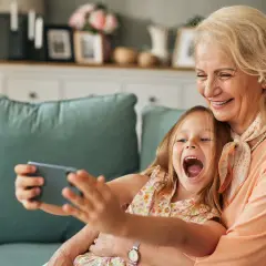 Großmutter und enkel kinder machen ein Selfie. Sie lachen beide vor Freude.