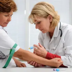 Lekarka pobiera krew od pacjentki do badań, w tym na obecność czynnika reumatoidalnego.