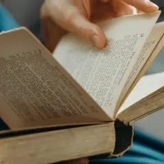Eine Hand blättert in einem alten Buch. Der Titel "Man and Superman" ist sichtbar. Ein guter historischer Roman zum Eintauchen.